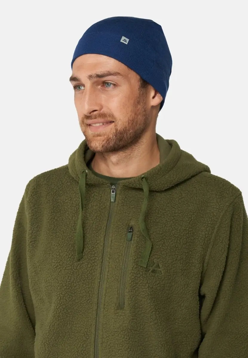 Person in a blue beanie and olive fleece jacket, facing left, smiling slightly.