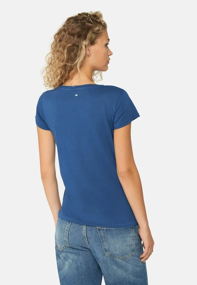Woman in blue crew neck t-shirt and jeans, viewed from the back, with curly hair.