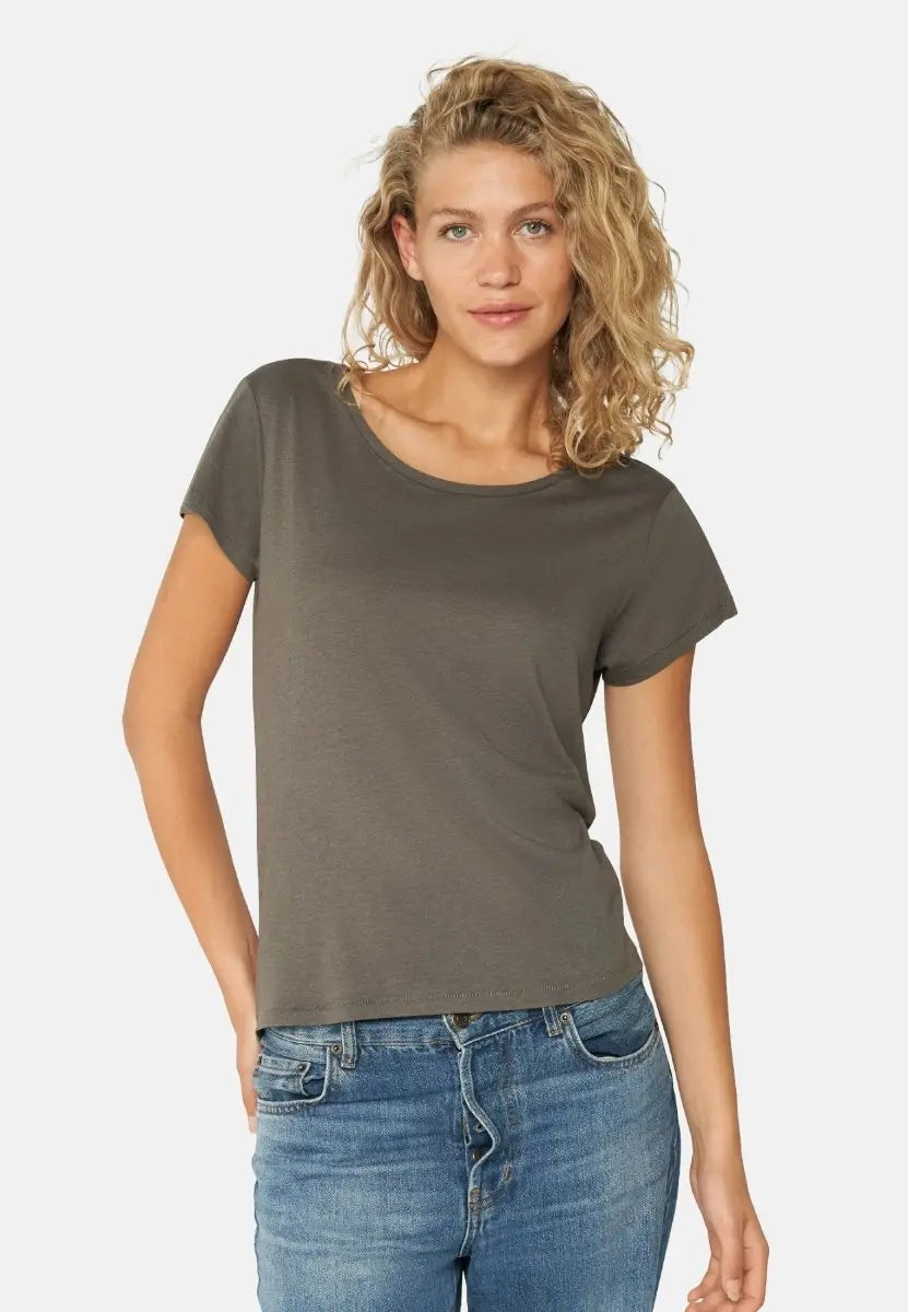 Woman in dark gray crew neck T-shirt and light blue jeans, standing with a casual pose.
