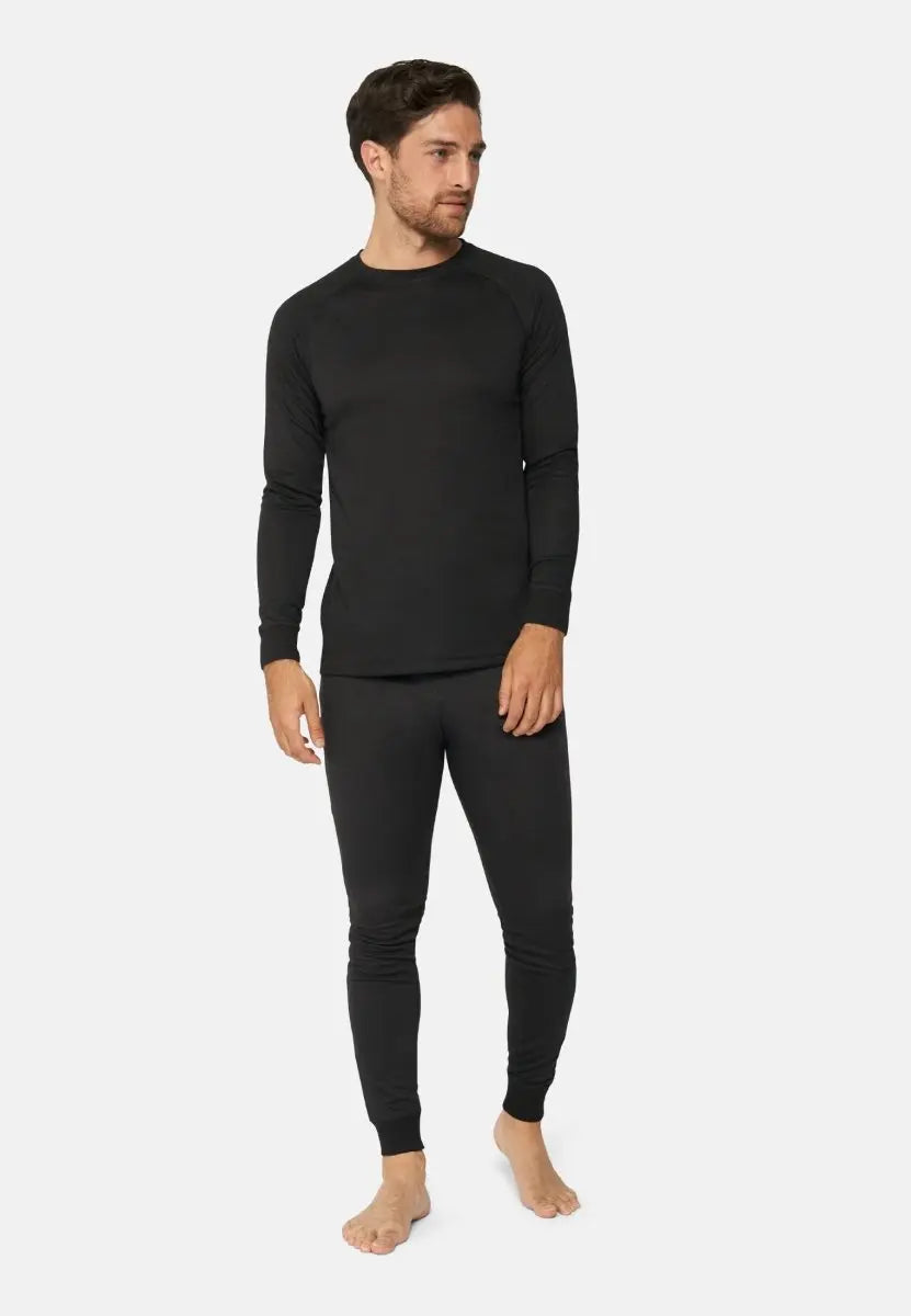 Person in black thermal top and leggings, barefoot, standing against a plain white background.