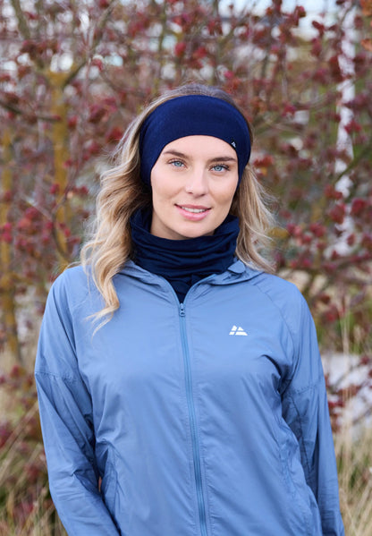 Person wearing a blue merino headband and jacket, standing outdoors with trees in the background.